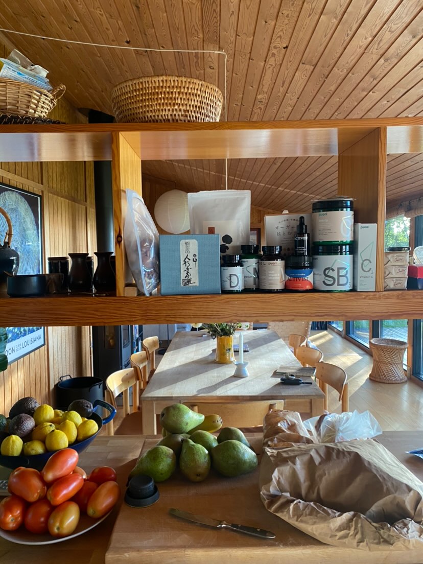 Kitchen shelves lined with jars and a bench covered in fruit.